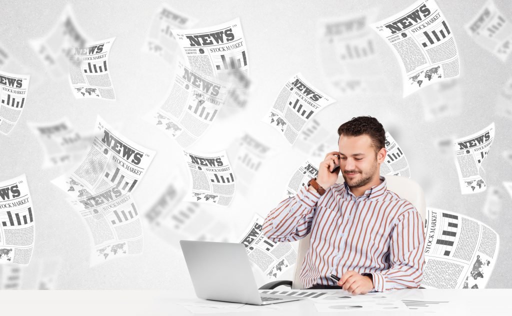 Businessman at desk with stock market newspapers